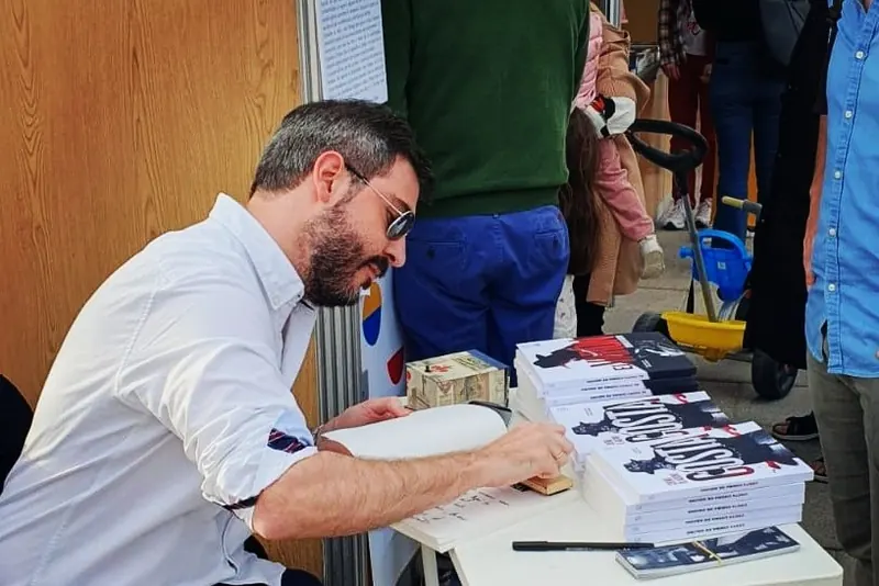 Chema de Aquino firmando un libro en una mesa de firmas